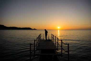 Siluet bir adamın içinde deniz günbatımı üzerinde yüzmek için hazırlanıyor