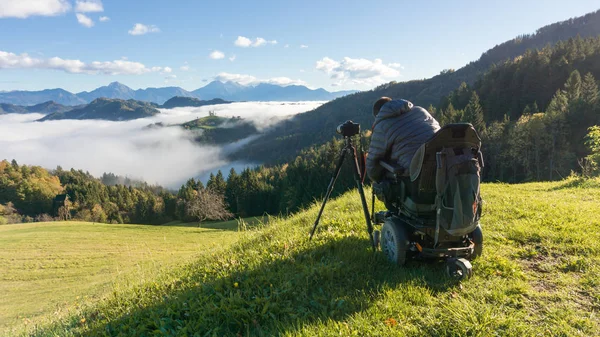 Hombre en silla de ruedas tomando fotos de hermoso paisaje en una mañana brumosa, Santo Tomás Eslovenia —  Fotos de Stock