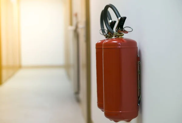 Extintor rojo en pasillo vacío en la pared blanca con resplandor solar — Foto de Stock