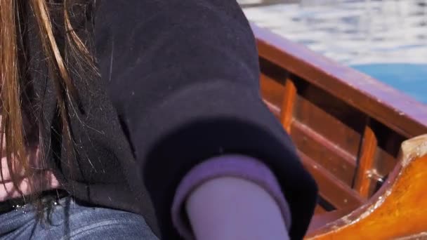 Slow motion z bliska: ręce młodej kobiety wiosło wioślarstwo w drewnianej łodzi na słoneczny dzień — Wideo stockowe