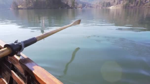 Vidéo 4K - Une pagaie dans l'eau par une journée ensoleillée - Ramer le bateau avec l'île Lac de Bled dans une réflection- Lac de Bled, Slovénie — Video