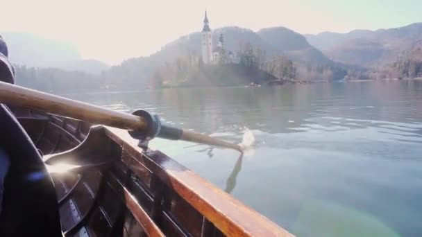 Vídeo 4K - Um remo na água em um dia ensolarado - Remo o barco com ilha Lago Bled no fundo Lago Bled, Eslovênia — Vídeo de Stock