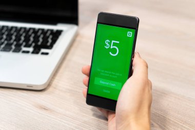 Smartphone cep telefonu ile bilgisayar dizüstü - Slovenya 13.02.2019 yanında insan eli tarafından tutulan nakit App kare Inc tarafından görüntülenen