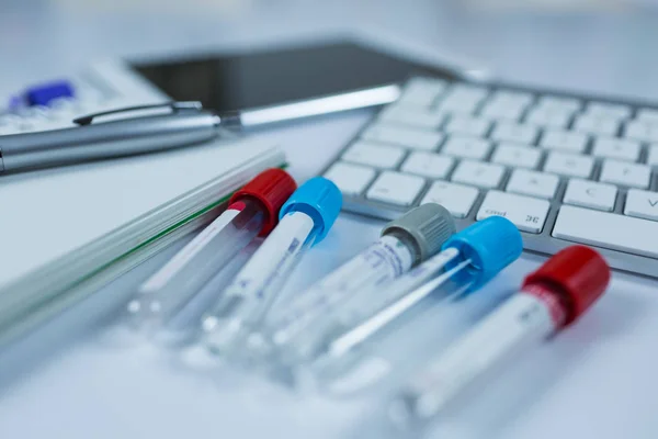 Buteleczki z lekami dla próbek obok komputera typu tablet i klawiatury komputera w medycynie, zbliżenie na białym tle — Zdjęcie stockowe