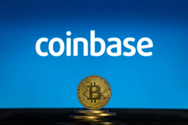 Coinbase-Logo auf einem Computerbildschirm mit einem Stapel Bitcoin-Kryptowährungen. — Stockfoto