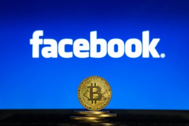 Bitcoin cryptocurency para yığını ile bilgisayar ekranında Facebook logosu.