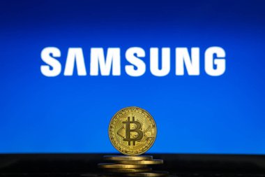 Samsung logo on a computer screen with a stack of Bitcoin cryptocurency coins. clipart