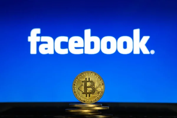 Facebook logo on a computer screen with a stack of Bitcoin cryptocurency coins. — Stock Photo, Image