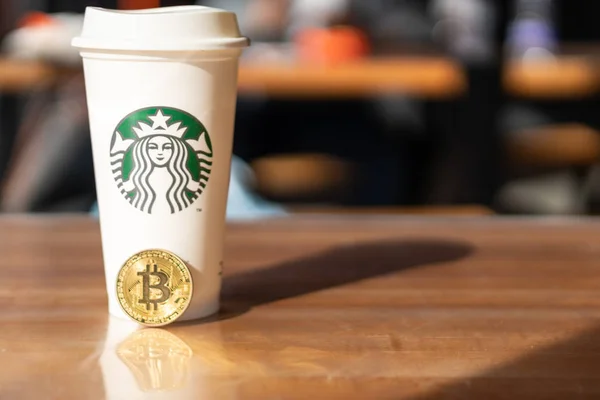 Kryptowährung Bitcoin neben Starbucks. Starbucks verabschiedet Blockchain-Konzept - Slowenien - 28.2.2019 — Stockfoto