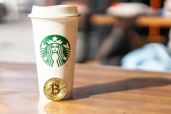 Kryptowährung Bitcoin neben Starbucks. Starbucks verabschiedet Blockchain-Konzept - Slowenien - 28.2.2019 — Stockfoto