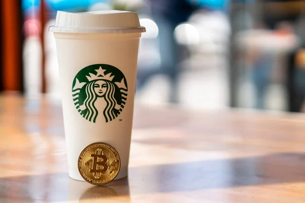 Kryptowährung Bitcoin neben Starbucks. Starbucks verabschiedet Blockchain-Konzept - Slowenien - 28.2.2019 — Stockfoto