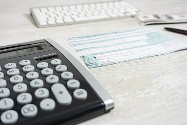 US tax form next to computer keyboard, calculator and tax form 1040. tax form us business income office hand fill concept