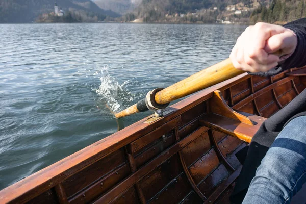Young woman using paddle on a wooden boat with island Bled behind it - Lake Bled Slovenia rowing on wooden boats — Stock Photo, Image