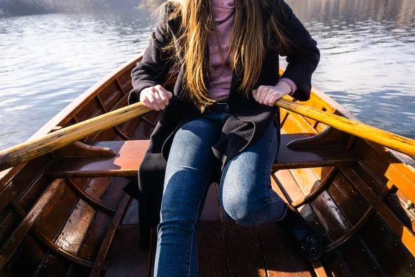 Young woman using paddle on a wooden boat - Lake Bled Slovenia rowing on wooden boats