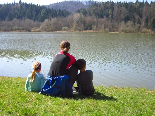 Мама с детьми сидит у озера — стоковое фото