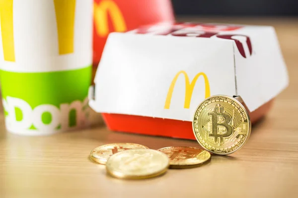 Ljubljana, Slowenien - 27. Dezember 2018: Big Mac Box mit mcdonalds Logo auf dem Tisch in mcdonalds Restaurant mit Bitcoin-Münzen daneben — Stockfoto