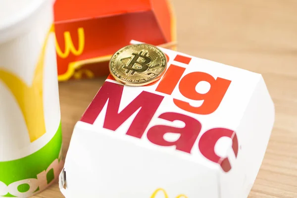 Ljubljana, Slowenien - 27. Dezember 2018: Big Mac Box mit mcdonalds Logo auf dem Tisch in mcdonalds Restaurant mit Bitcoin-Münzen daneben — Stockfoto