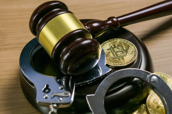 木製の机の上にビットコインと手錠をかけたガベルと手錠。暗号通貨の法的概念. — ストック写真