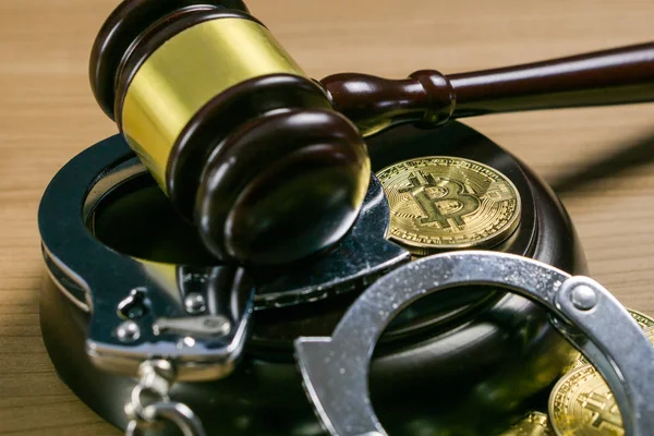 木製の机の上にビットコインと手錠をかけたガベルと手錠。暗号通貨の法的概念. — ストック写真