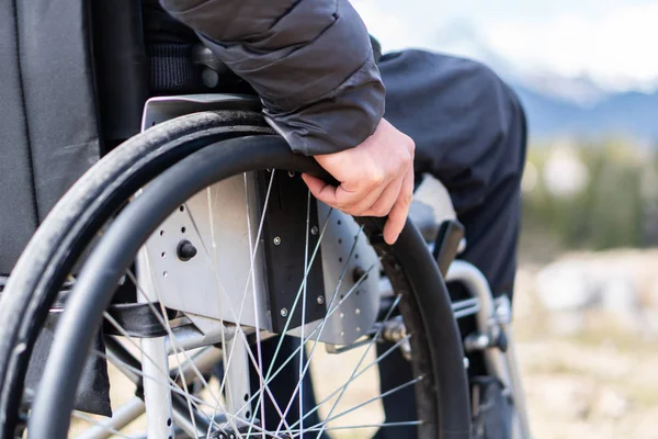 Photo rapprochée de Jeune homme handicapé tenant un fauteuil roulant à l'extérieur dans la nature observant les montagnes et la nature — Photo