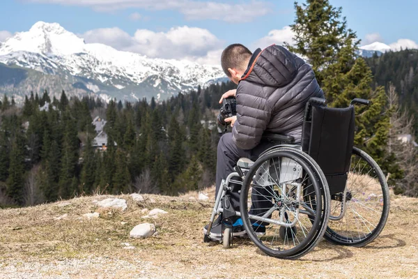 自然の中でカメラを使って車椅子に乗った障害者、美しい山々を撮影 — ストック写真