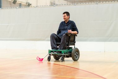 Disabled man on an electric wheelchair playing sports, powerchair hockey. IWAS - International wheelchair and amputee sports federation clipart