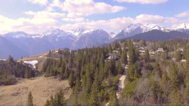 Fast flying over the beautiful Velika planina full of spruce, little houses and mountains in the back. Aerial camera shot. Landscape panorama sunny day. Slovenia — Stock Video