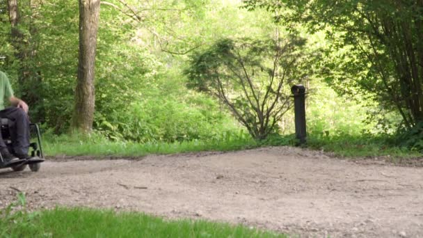 Movimiento lento del hombre en una silla de ruedas que conduce fuera de la carretera con obstáculo en la carretera. minusválidos problema concepto — Vídeos de Stock