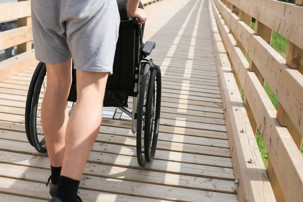 Assistant et jeune homme handicapé en fauteuil roulant — Photo