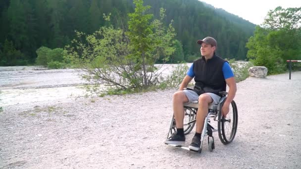 Медленное движение молодого студента-инвалида в инвалидной коляске, наблюдающего за природой вокруг него — стоковое видео