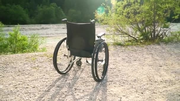 Slowmotion van lege rolstoel buiten in de zomer zonnige Park met felle zon op achtergrond groen natuur verhogen zon gezondheidszorg Lifestyle fysieke revalidatie concept niemand buiten — Stockvideo