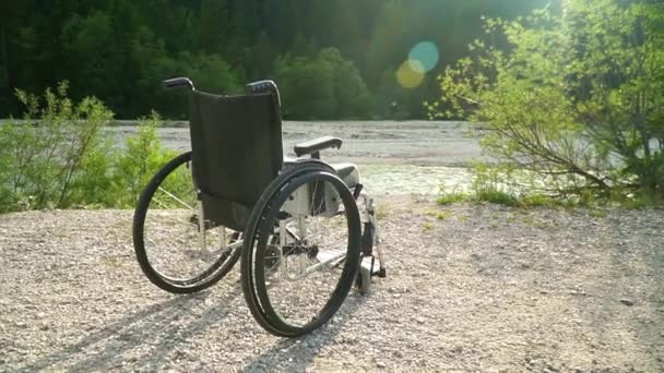 Slowmotion of empty wheelchair outside in summer sunny park with bright sunshine on background green nature raising sun healthcare lifestyle physical rehabilitation concept nobody outdoor — Stock Video