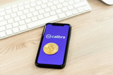 12 Temmuz 2019, Ljubljana Slovenya - Üzerinde Calibra logosu bulunan akıllı telefon, Bitcoin sikkesi yanında. İşlemler için Facebooks yeni küresel kripto para birimi