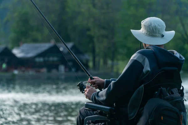 Joven en silla de ruedas pescando en el hermoso lago al atardecer, amanecer —  Fotos de Stock