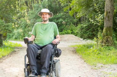 Portrait photo of a handicapped man in a electric wheelchair in nature clipart