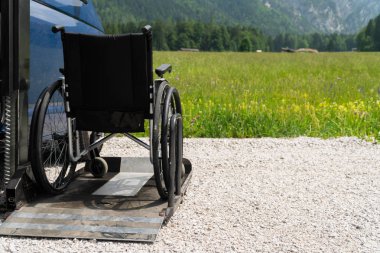 Engelli insanlar için siyah elektrikli Asansör özel araç. Arkada doğa ve dağlar olan bir rampa üzerinde boş tekerlekli sandalye
