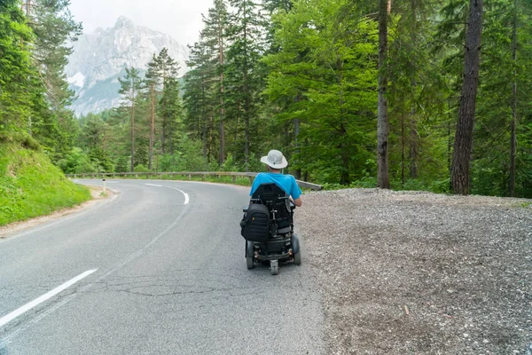 Persona con discapacidad en una silla de ruedas eléctrica que conduce en la calle, carretera — Foto de Stock