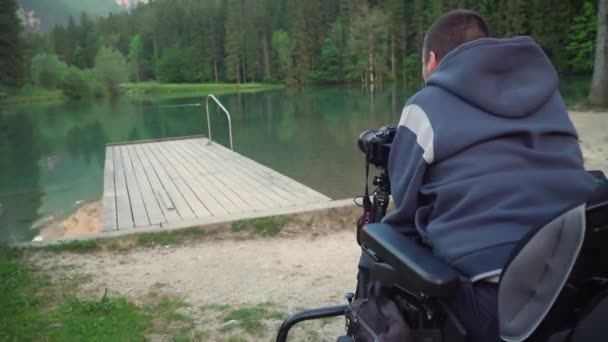 4K upplösning video av en man tar foto med DSLR kamera av vacker sjö och berg i ryggen — Stockvideo