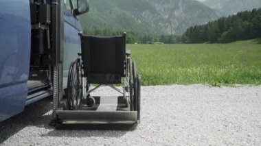 Engelli kişiler için elektrik Lift özel araç 4k çözünürlüklü video. Arkada doğa ve dağlar olan bir rampa üzerinde boş tekerlekli sandalye. Engelli insanlar kavramı için Self yardım