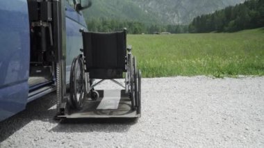Engelli kişiler için elektrik Lift özel araç 4k çözünürlüklü video. Arkada doğa ve dağlar olan bir rampa üzerinde boş tekerlekli sandalye. Engelli insanlar kavramı için Self yardım