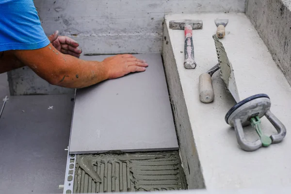 The hands of the tiler are laying the ceramic tile on the floor. — Stock Photo, Image