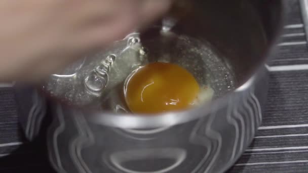 Női kezek csinos egy tojást a tálba. Egy tojás feltörése a konyhában. Lassított mozgás. — Stock videók
