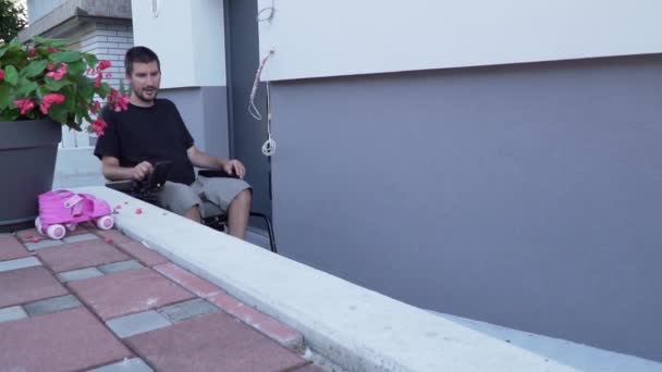 Slowmotion video van een man in een elektrische rolstoel met behulp van een hellingbaan bij toegankelijk huis — Stockvideo