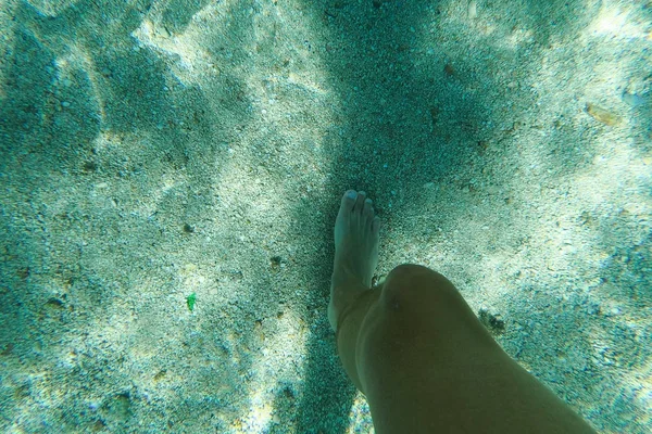 Ноги пешком по пляжу идеальный белый песок бирюзовой воды, отражающийся от солнца. Подводное фото — стоковое фото
