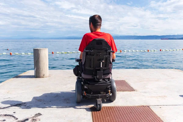 Homme assis dans un fauteuil roulant sur la plage — Photo