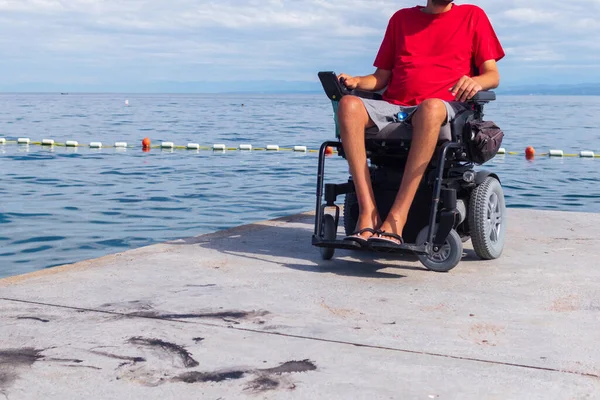 Homem sentado em uma cadeira de rodas na praia — Fotografia de Stock