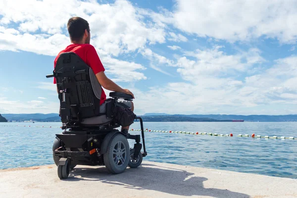 Hombre sentado en una silla de ruedas en la playa — Foto de Stock