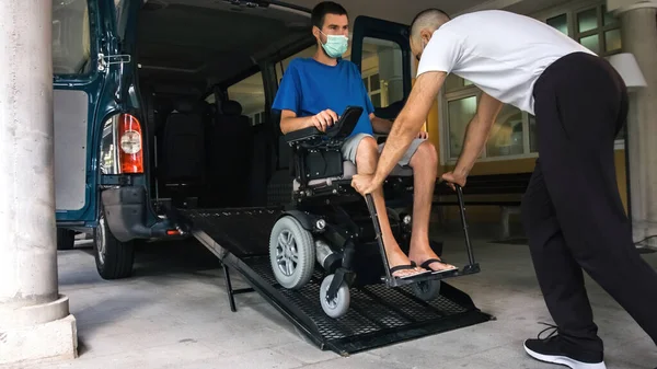 Tekerlekli sandalyedeki adam araç rampası kullanıyor.