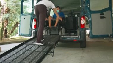 Tekerlekli sandalyedeki adam araç rampası kullanıyor.