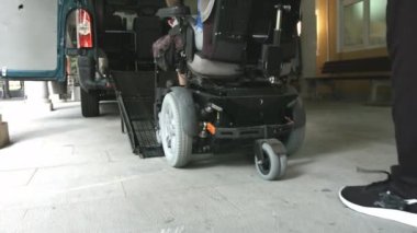 Tekerlekli sandalyedeki adam araç rampası kullanıyor.